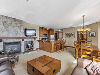 This stunning property boasts a cozy living area with a stone fireplace and a mounted TV, perfect for relaxing evenings.