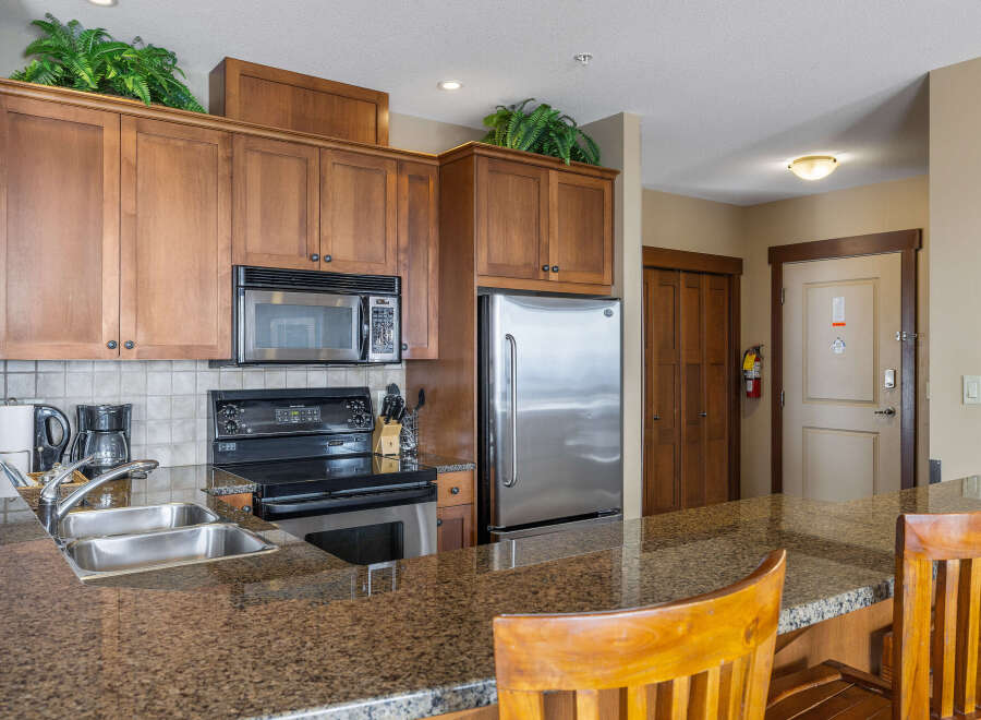 This stunning kitchen boasts beautiful wooden cabinetry, a modern stainless steel refrigerator, and a sleek microwave.