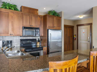This stunning kitchen boasts beautiful wooden cabinetry, a modern stainless steel refrigerator, and a sleek microwave.