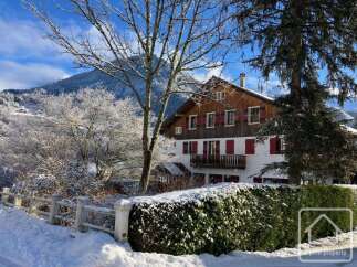 Nestled in a picturesque winter wonderland, this charming property boasts a stunning facade with traditional wooden accents and vibrant red shutters.