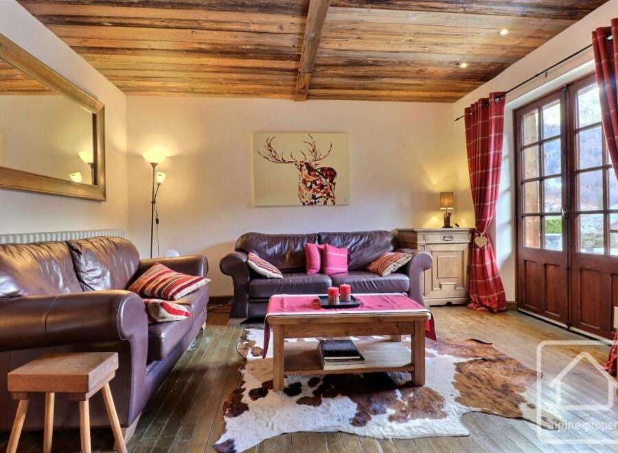 This charming property boasts a cozy living room with rustic wooden beams and a cowhide rug, creating a warm and inviting atmosphere.