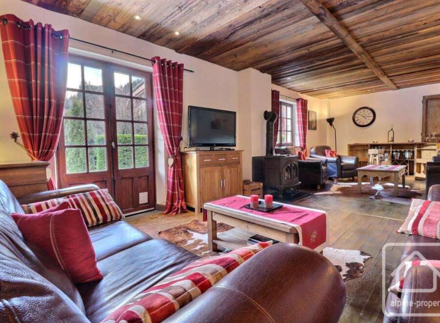 Experience the charm of this stunning property, featuring a cozy living room with a fireplace and a rustic wooden ceiling.