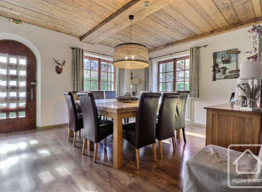 This charming dining room features a rustic wooden ceiling and a large dining table, perfect for family gatherings.