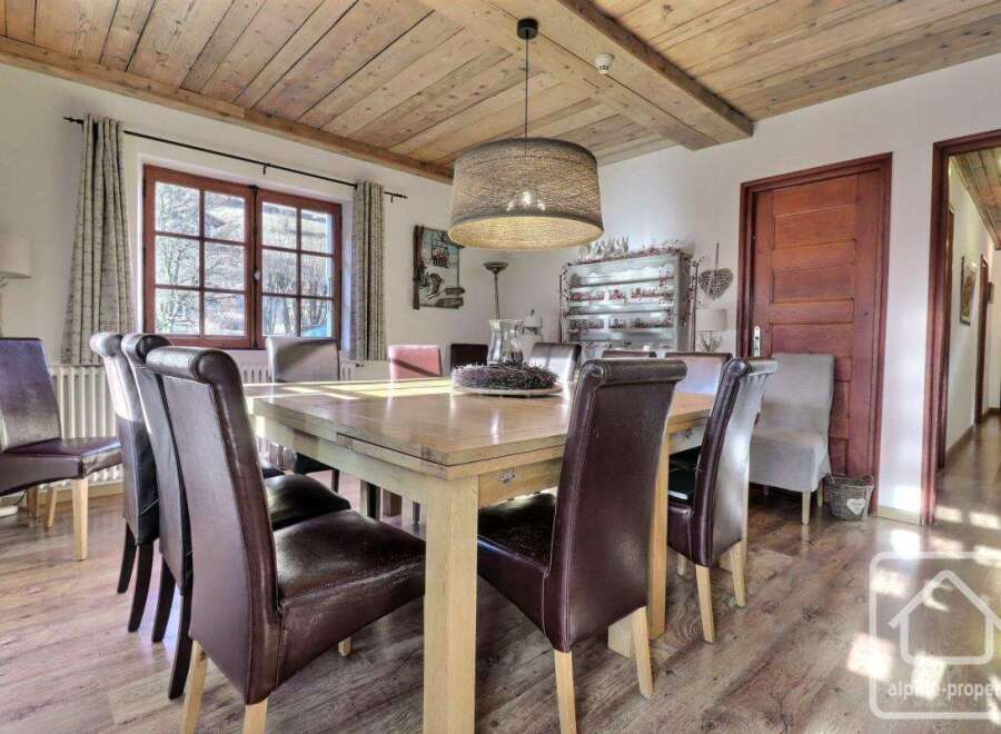 This charming dining room features a rustic wooden ceiling and a large, inviting dining table, perfect for family gatherings.