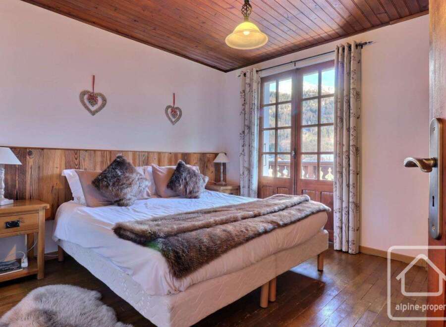 Discover the charm of this cozy bedroom, featuring a comfortable bed adorned with plush pillows and a warm fur throw.
