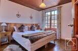 Discover the charm of this cozy bedroom, featuring a comfortable bed adorned with plush pillows and a warm fur throw.