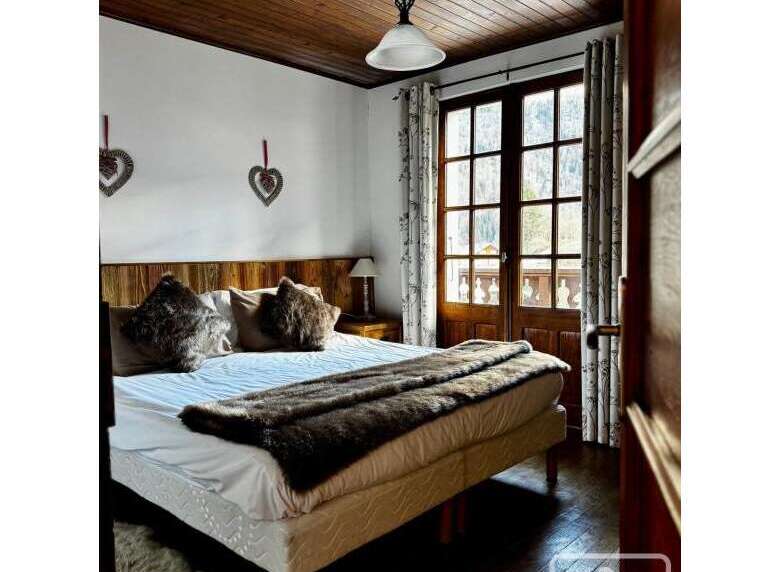 This cozy bedroom features a rustic wooden ceiling and a comfortable bed with plush pillows and a faux fur throw.