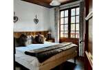 This cozy bedroom features a rustic wooden ceiling and a comfortable bed with plush pillows and a faux fur throw.