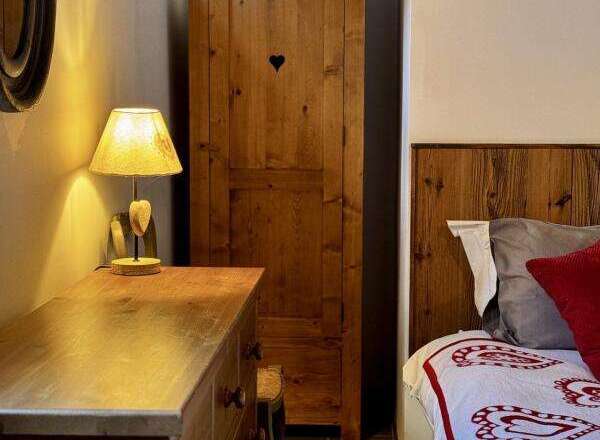 Discover the charm of this cozy bedroom featuring a rustic wooden wardrobe with a heart-shaped detail.