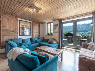 Step into this cozy living space, featuring a plush teal sectional and a rustic wooden ceiling.