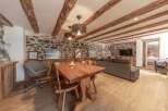 Discover the charm of this rustic retreat, featuring exposed wooden beams and a stunning stone wall.