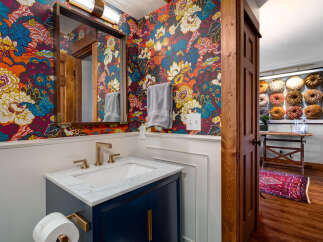 Step into this stylish bathroom featuring a vibrant floral wallpaper that adds a pop of color and personality.