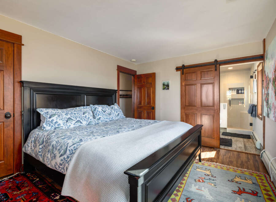 This stunning bedroom boasts a luxurious black bed frame and elegant wooden doors, creating a warm and inviting atmosphere.