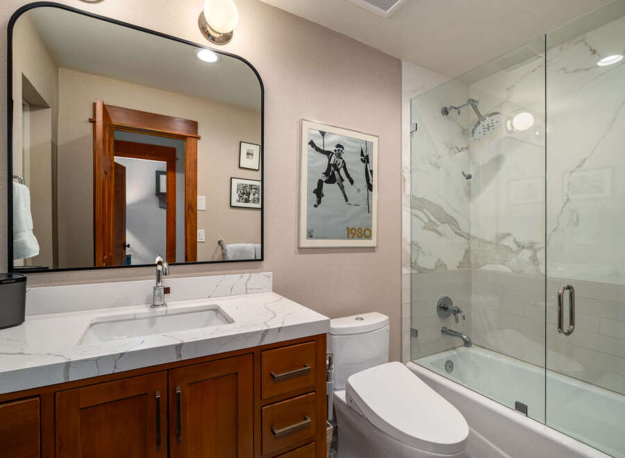 Step into a beautifully designed bathroom featuring a modern vanity with a marble countertop and a sleek, framed mirror.