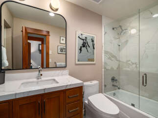 Step into a beautifully designed bathroom featuring a modern vanity with a marble countertop and a sleek, framed mirror.