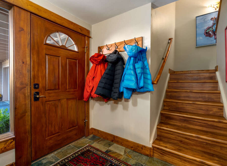 Step inside this inviting entryway, showcasing a stunning wooden door and a practical coat rack.