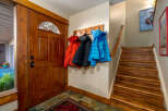 Step inside this inviting entryway, showcasing a stunning wooden door and a practical coat rack.