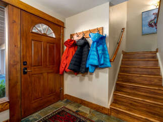 Step inside this inviting entryway, showcasing a stunning wooden door and a practical coat rack.