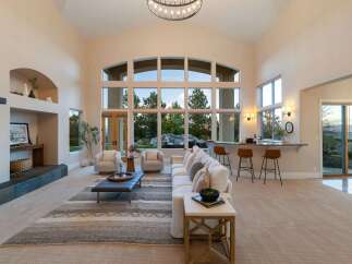 Experience luxury living in this stunning property, featuring a spacious living area with soaring ceilings and expansive windows that flood the space with natural light.