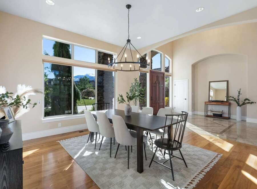Step into luxury with this stunning dining room, featuring a modern chandelier and a large dining table perfect for hosting.