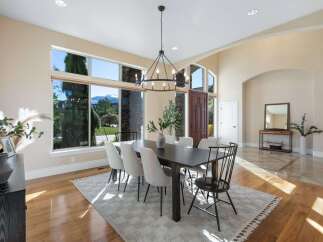 Step into luxury with this stunning dining room, featuring a modern chandelier and a large dining table perfect for hosting.