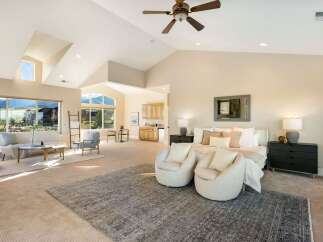 Experience luxury living in this stunning property, featuring a spacious master suite with a cozy seating area.