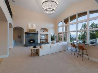 Experience luxury living in this stunning property featuring a grand living room with soaring ceilings and a cozy fireplace.