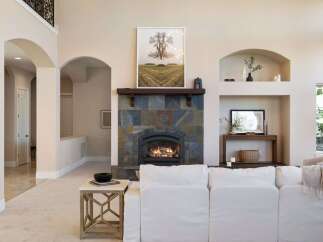 This stunning living room boasts a cozy fireplace with a beautiful stone surround, perfect for those chilly evenings.
