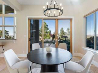 Experience luxury living in this stunning property! This dining area features a modern round table, elegant chairs, and a beautiful chandelier.