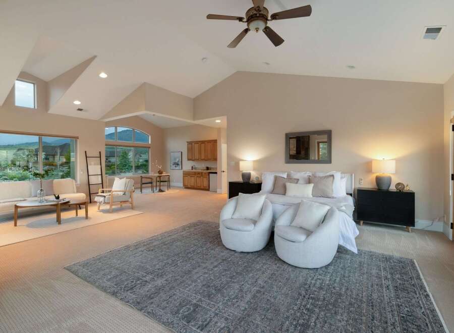 Experience luxury living in this stunning property, featuring a spacious master suite with a cozy seating area and a stylish rug.