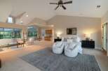 Experience luxury living in this stunning property, featuring a spacious master suite with a cozy seating area and a stylish rug.