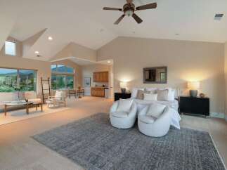Experience luxury living in this stunning property, featuring a spacious master suite with a cozy seating area and a stylish rug.