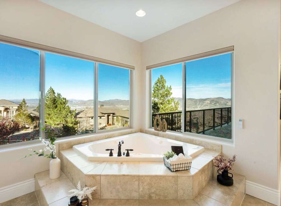Indulge in luxury with this stunning bathroom featuring a corner jacuzzi tub and breathtaking views.