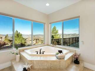 Indulge in luxury with this stunning bathroom featuring a corner jacuzzi tub and breathtaking views.