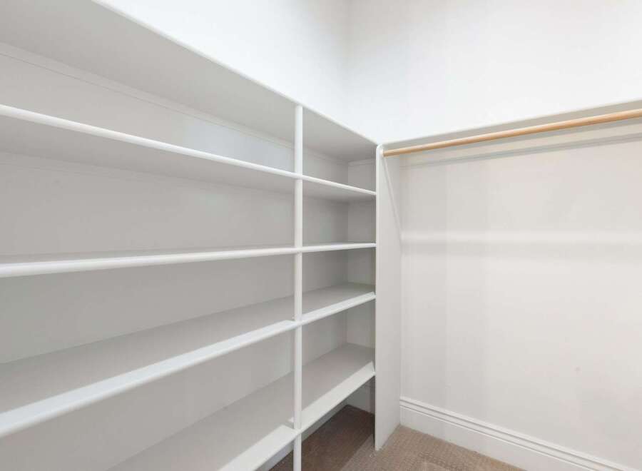 This spacious walk-in closet offers ample storage with its built-in shelving and hanging rod.