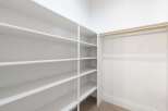 This spacious walk-in closet offers ample storage with its built-in shelving and hanging rod.