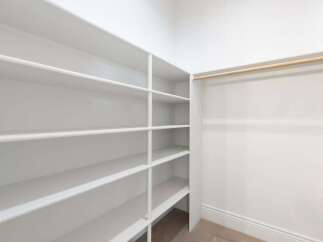 This spacious walk-in closet offers ample storage with its built-in shelving and hanging rod.