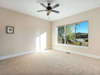 This spacious room offers a serene atmosphere with its neutral color palette and abundant natural light.