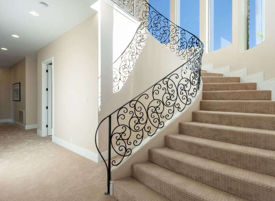 This stunning property features a grand staircase with intricate wrought iron railings, adding a touch of elegance to the home.