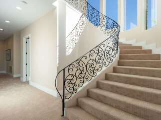 This stunning property features a grand staircase with intricate wrought iron railings, adding a touch of elegance to the home.