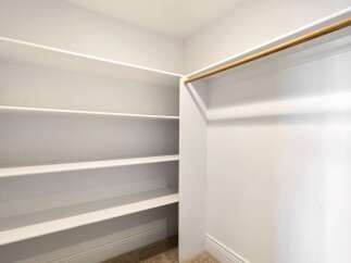 Step into this spacious walk-in closet, offering ample storage with its multiple shelves.
