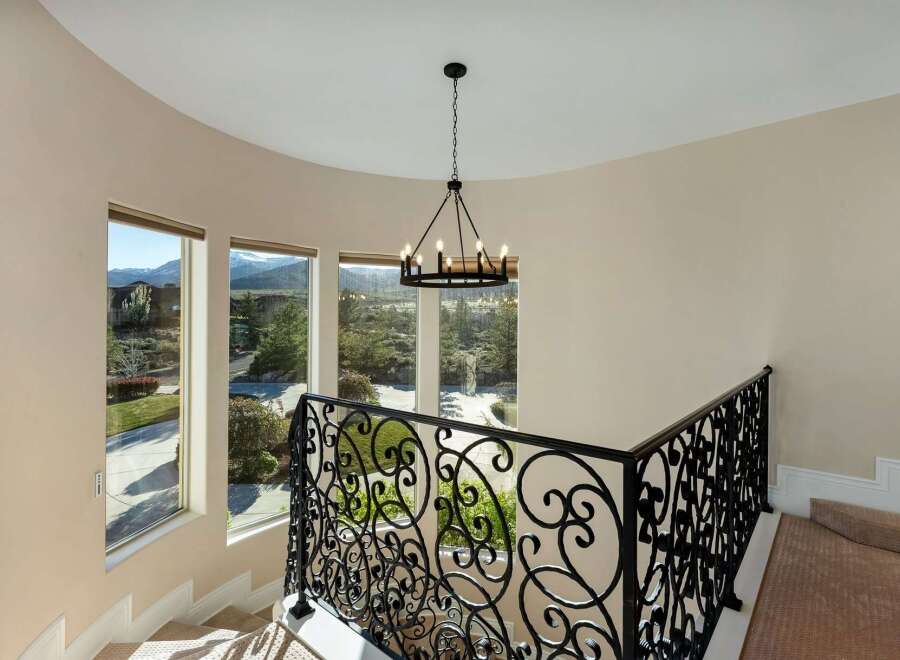 Elegant staircase with wrought iron railing and a stunning chandelier.
