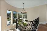 Elegant staircase with wrought iron railing and a stunning chandelier.