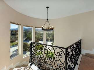 Elegant staircase with wrought iron railing and a stunning chandelier.