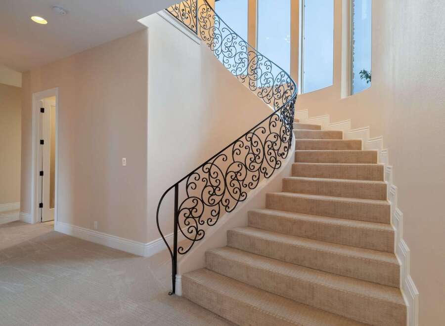 This stunning property boasts a grand staircase with intricate wrought iron railings, adding a touch of elegance to the home.