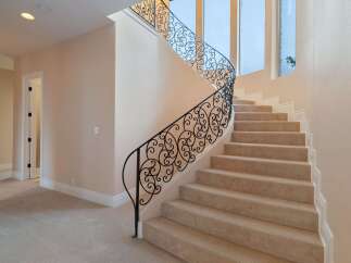This stunning property boasts a grand staircase with intricate wrought iron railings, adding a touch of elegance to the home.