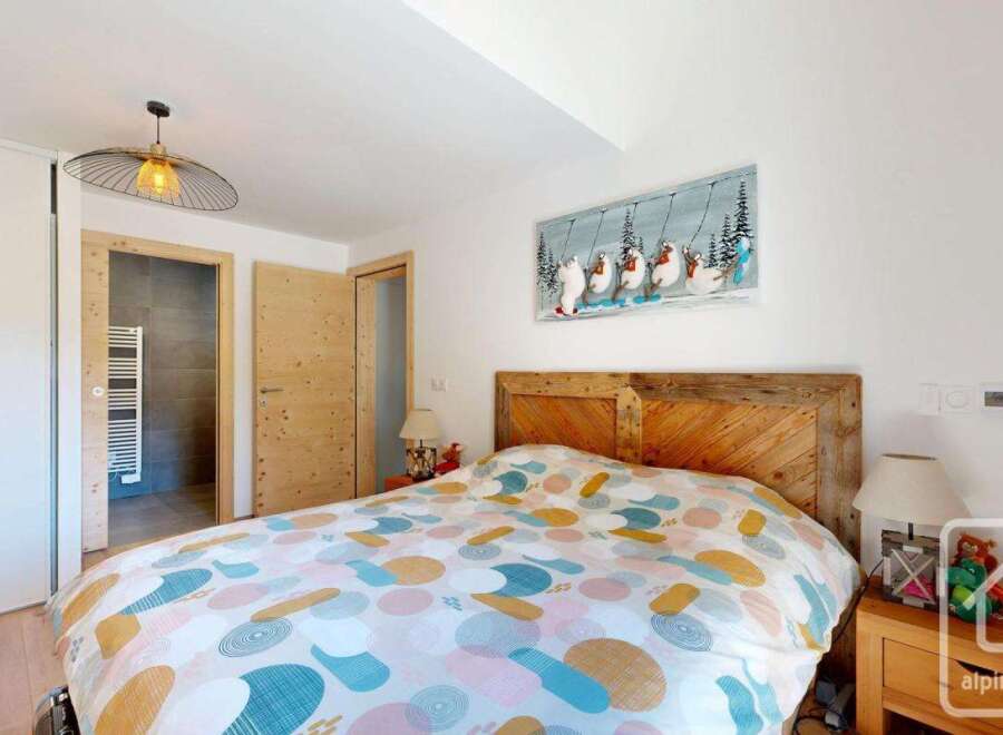 This cozy bedroom features a rustic wooden headboard and a colorful patterned duvet, creating a warm and inviting atmosphere.