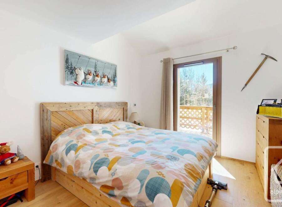 This charming bedroom boasts a rustic wooden bed frame and a colorful patterned duvet, creating a cozy and inviting atmosphere.