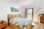 This charming bedroom boasts a rustic wooden bed frame and a colorful patterned duvet, creating a cozy and inviting atmosphere.