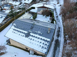 This stunning property boasts a modern design with a sleek, snow-covered roof, offering a unique aesthetic.